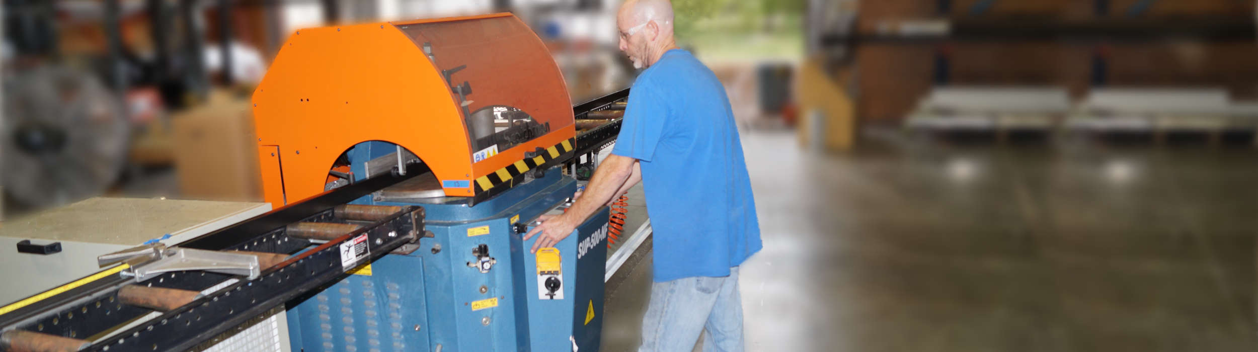Operator running aluminum stock through a precision cut-off saw