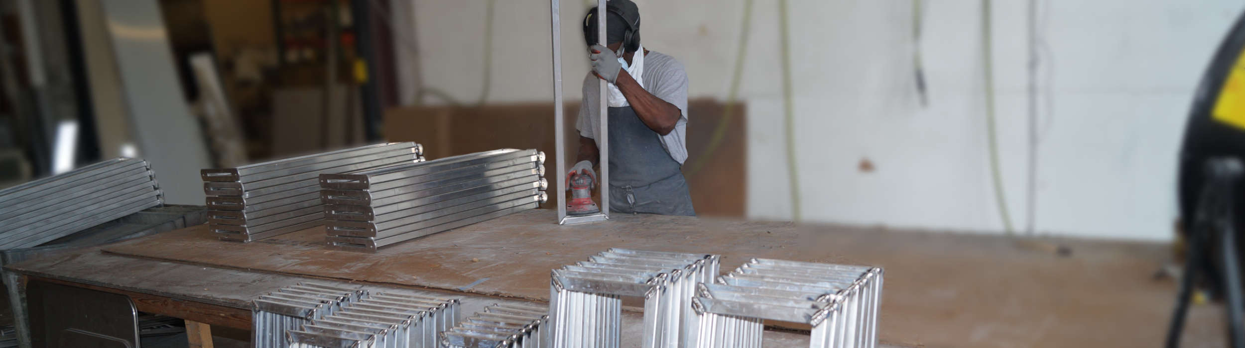 Worker finishing aluminum components on a benchtop