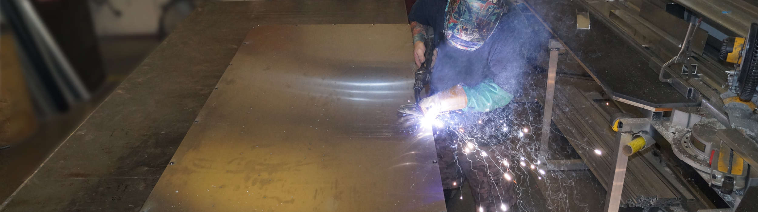 Technician welding an aluminum sign panel with sparks flying